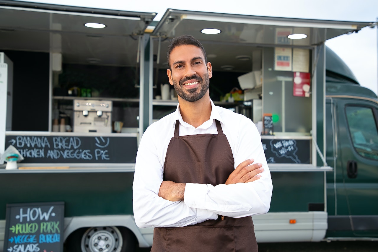 cheerful ethnic male small business owner standing with crossed arms